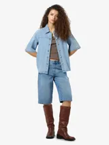 Camisa de denim celeste con cuello clásico, mangas cortas y cierre con botones.