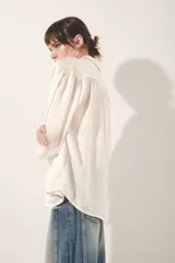 Camisa color blanco hueso de corte fluido, con cuello camisero, mangas largas abullonadas con puño abotonado y detalle de frunces.