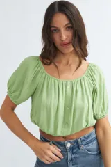 Blusa crop verde claro con mangas abullonadas y botones frontales.