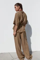 Pantalón marrón de tiro alto con cintura elástica, bolsillos delanteros y pernera ancha.