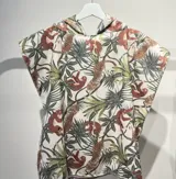 Poncho toalla con capucha, estampado con diseño de hojas y mariposas en tonos rosa, naranja y gris sobre fondo celeste.