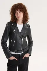 Campera biker negra de cuero sintético con cuello solapa, cierre cruzado con cremallera, bolsillos con cremallera y cinturón ajustable.
