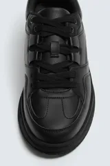 Zapatilla deportiva negra de estilo retro con suela de goma con volumen.