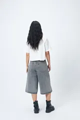 Bermuda de jean negra, de corte amplio y largo por debajo de la rodilla.