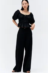 Pantalón negro de lino, de tiro alto, corte ancho y bolsillos laterales.