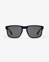 Lentes de sol Hawkers unisex con montura rectangular negra y lentes grises.