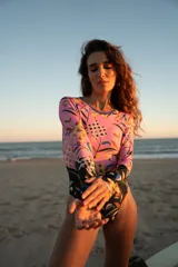 Enterito de lycra reciclada con protección solar SPF 50, manga larga y cuello redondo. Estampado floral en tonos rosados, amarillos y azules con mangas y parte inferior en negro con estampado floral.