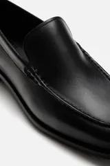Mocasín de cuero negro con suela a tono y ligero tacón.