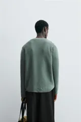 Sweater azul de punto con textura, corte holgado, cuello redondo y mangas largas con puños acanalados.