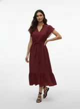 Vestido midi color vino (Syrah) con escote en V y lazos ajustables en el cuello. Posee mangas cortas con detalle de calado (encaje o bordado) y un lazo para ajustar la cintura. La falda es escalonada con un volante en el ruedo.
