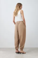 Pantalón tipo barrel color tostado, confeccionado en lino, con cintura elástica y cordón ajustable.