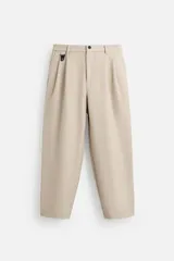 Pantalón color beige de corte ancho, con cintura elástica, pliegues frontales, bolsillos laterales y traseros de vivo.