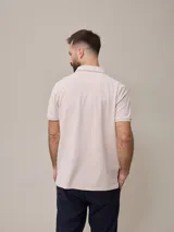 Chomba manga corta color beige con cuello clásico y tapeta de dos botones. Tiene un pequeño logo bordado en el pecho. Corte clásico.