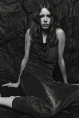 Vestido largo de fiesta confeccionado con hilo metalizado color marrón. Tiene cuello halter con lazada, escote drapeado, espalda descubierta con tira ajustable y cierre lateral con cremallera oculta.