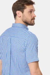 Camisa de manga corta con estampado a cuadros azules y blancos, bolsillo en el pecho con logo bordado y botones personalizados. Hecha en Uruguay.