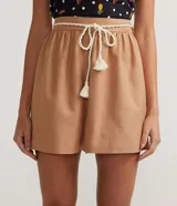 Short ancho color marrón claro, confeccionado en algodón, viscosa, modal y lino. Presenta pliegues y cordón trenzado en la cintura.