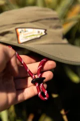 Sombrero tipo pescador color beige con ala ancha, borde reforzado, correa ajustable y parche frontal con el logo de Denali.