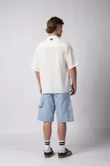 Camisa de lino color blanco, de manga corta, con cuello clásico y cierre frontal con botones.