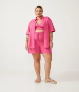 Conjunto de lino color rosa compuesto por un top estilo corpiño con elástico en la parte inferior, shorts con cordón ajustable y camisa de manga corta con botones.