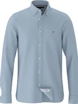 Camisa celeste de Tommy Hilfiger, corte slim, confeccionada en tejido dobby de algodón orgánico con tecnología TH Flex, cuello abotonado, mangas largas con puños redondeados con dos botones y logo bordado en el pecho.