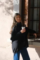 Polerón negro de corte oversize, con cuello drapeado y mangas largas caídas.