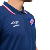 Remera polo azul marino con cuello clásico y puños con detalles tricolor (blanco, rojo y azul). Presenta logo de la marca Umbro bordado en blanco y escudo del Club Nacional de Football bordado en el pecho. Fabricada en tejido suave y respirable.