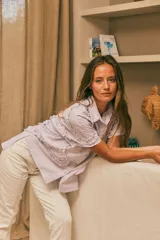 Camisa celeste a rayas verticales con volados en el frente y mangas cortas.