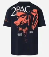 Remera negra de algodón con corte relaxed, cuello redondo y mangas cortas. Estampa frontal con una cruz y el nombre "Tupac Shakur" en color naranja.