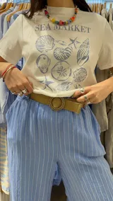 Pantalón de lino azul marino con rayas verticales blancas, corte palazzo, cintura alta con elástico y cinturón de raffia con hebilla redonda.