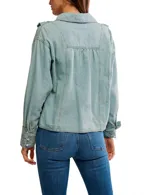 Camisa amplia de chambray celeste con botones al frente y detalles de volados. Tiene cuello clásico, pliegues y hombros caídos.