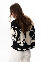 Chaqueta color crudo con bordados florales en tonos rojo, verde y negro.