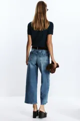 Pantalón de jean azul de corte culotte, tiro alto, pernera ancha y corta. Incluye cinturón marrón de gamuza con hebilla metálica.