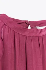 Top color fucsia de cuello halter con volantes en el mismo tejido. Cierre en la espalda con abertura y botones.