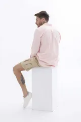 Camisa rosa de manga larga con cuello clásico y cierre frontal con botones. Corte recto.