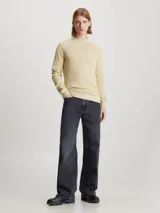Sweater color crema de algodón con textura de canalé, cuello redondo e insignia de Calvin Klein Jeans bordada en el pecho.