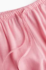 Pantalón de tiro bajo color rosa, confeccionado en tejido liviano con lino en la trama. Presenta elástico revestido y cordón para ajustar en la cintura, bolsillos al bies y piernas rectas.