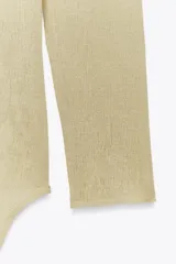 Top color crema de punto, con cuello redondo, manga larga y detalle de bajo superpuesto.