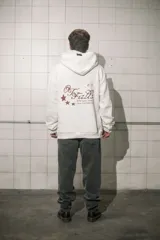 Hoodie color crema de algodón con capucha, bolsillo tipo canguro y estampado pequeño en el pecho.