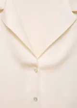 Camisa color crema de manga corta con tejido satinado, corte regular, cuello camisero y cierre delantero con botones.
