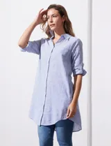 Camisola larga de algodón color blanco, marca Dash. Tiene cuello con solapa, abertura central con botones, bolsillo aplicado en el pecho, mangas regulables con presilla y botón, y bolsillos laterales en la costura.