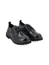 Zapato acordonado de cuero negro con suela track y detalle de pespuntes en color crudo.