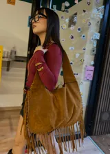 Cartera de hombro grande de gamuza color camel con flecos en el borde inferior.