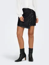 Minifalda negra de cuero sintético con corte cruzado y tachas plateadas en forma de estrella.