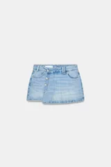 Falda pantalón corta de denim celeste, de tiro alto con cinco bolsillos y cierre frontal cruzado con botones metálicos.