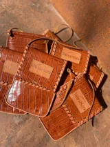 Cartera bandolera color marrón con textura croco, con correa fina y logo de la marca Sierra Mora.