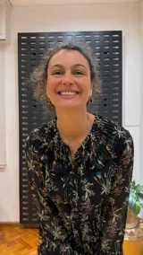 Vestido midi negro con estampado floral, mangas largas y cuello con volantes plisados.