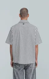Camisa de manga corta con cuello abierto y corte oversize, a rayas verticales blancas y negras.