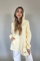 Canguro oversize color manteca con capucha y mangas largas con puños elásticos.
