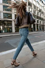 Pantalón de jean azul de tiro alto, corte mom fit, tobillero y con cinco bolsillos. Cierre frontal con cremallera y botón.