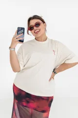 Remera color crema de corte holgado con estampado en la espalda de una copa de cóctel con cerezas y el número 888 en color rojo.